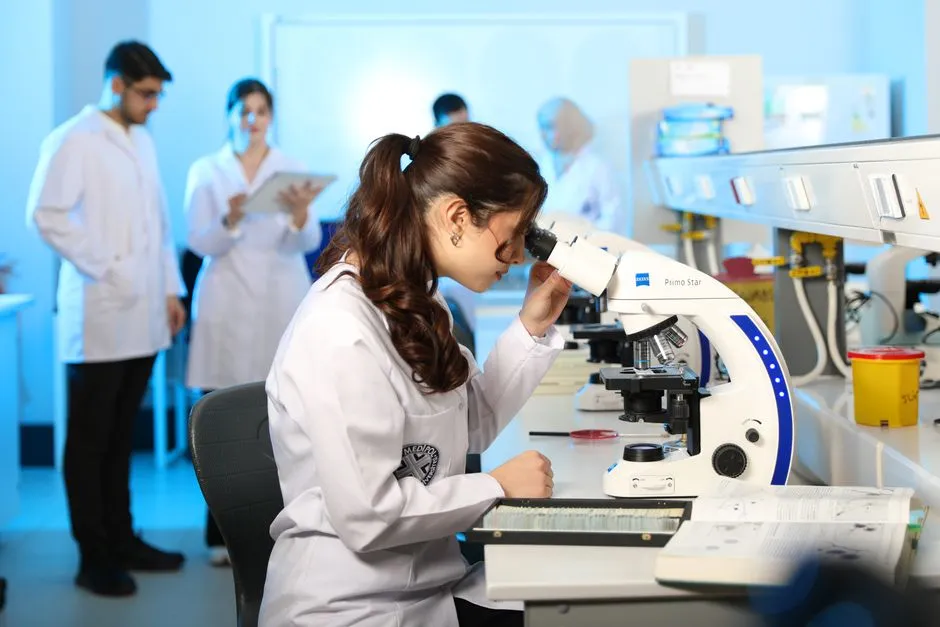 Student examining a sample under a microscope in a science laboratory